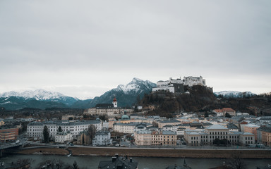 Panoramic view of Salzburg against snowcapped mountains and overcast sky