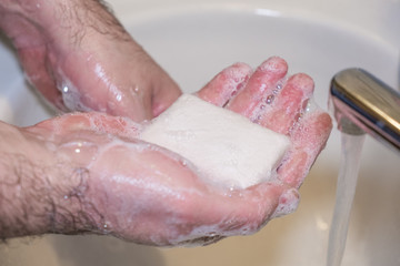 Fototapeta premium Personal hygiene and prevention of the coronavirus pandemic wash men's hands with soap and water.