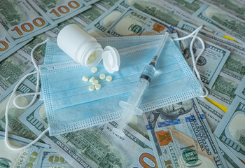 Concept of the global crisis due to coronavirus. Cash dollars, medical face masks, a bottle of pills. Pharmaceutics.