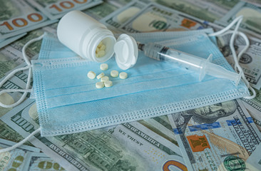 Concept of the global crisis due to coronavirus. Cash dollars, medical face masks, a bottle of pills. Pharmaceutics.
