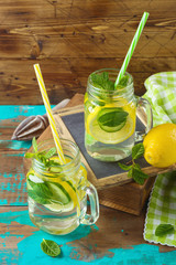 Infused water with lemon, cucumber and mint leaves over wooden background. Detox and healthy lifestyle concept.