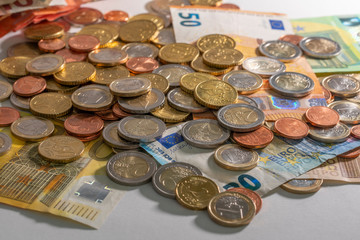 Bunch of euro coins on top of Euro banknotes. White background. Different coins from cents to two Euro.