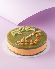 Vegan sea buckthorn and kiwi raw cake on paper background. Minimalist food photography.