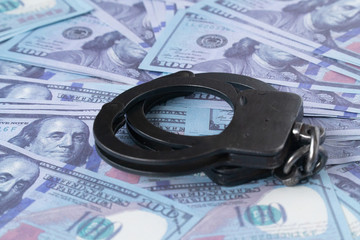handcuffs against the background of hundred-dollar bills