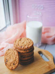 Oatmeal chocolate chip cookies with cinnamon and a glass of milk. Cookies on a wooden cutting board.
