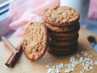 Oatmeal chocolate chip cookies with cinnamon and a glass of milk. Cookies on a wooden cutting board.