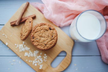 Oatmeal chocolate chip cookies with cinnamon and a glass of milk. Cookies on a wooden cutting board.