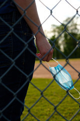 Images of young man wearing a COVID-19 mask at a closed baseball field.