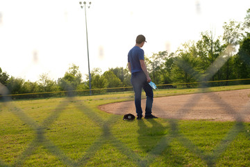 Images of young man wearing a COVID-19 mask at a closed baseball field.