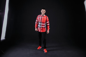 young guy in a plaid shirt posing on a black background photo studio
