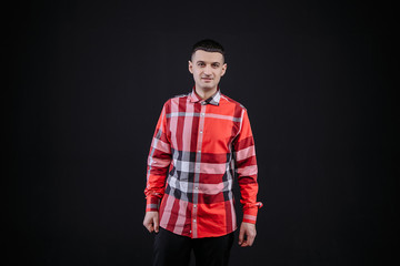 young guy in a plaid shirt posing on a black background photo studio