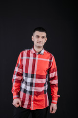 young guy in a plaid shirt posing on a black background photo studio
