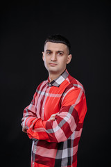 young guy in a plaid shirt posing on a black background photo studio