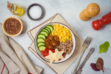 Buddha bowl with buckwheat, tomatoes, cucumber, red sweet pepper and corn on rustic table. Top view from above