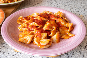 Italian pasta called orecchiette. Plate of delicious orecchiette with tomato sauce Ragù and meat