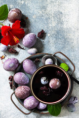 Natural egg dye purple. Easter eggs are painted with natural egg dye from Hibiscus tea on a gray stone countertop. Top view flat lay background. Copy space.
