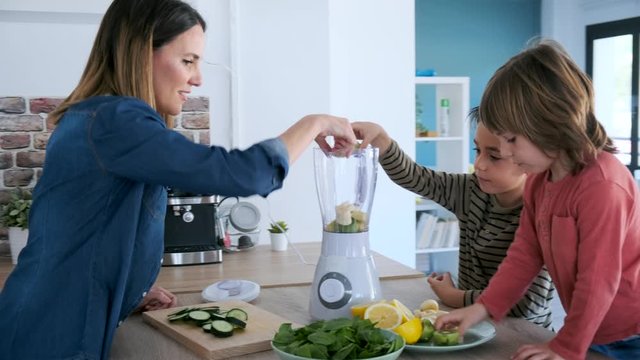 Video of two boys helping his mother to prepare a detox juice with blender in the kitchen at home.