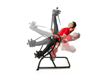 Man doing exercise on inversion table for his back pain, isolated on white. Multiple positions.