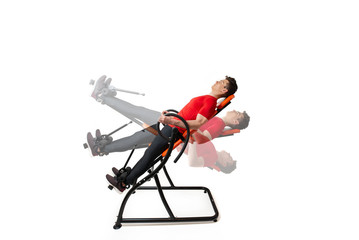 Man doing exercise on inversion table for his back pain, isolated on white. Multiple positions.