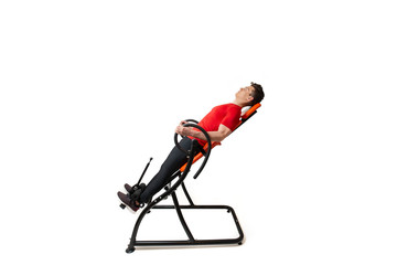 Man doing exercise on inversion table for his back pain, isolated on white