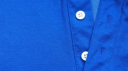 Closeup of new and good quality of bright dark blue shirt with simple white buttons stitched on the...