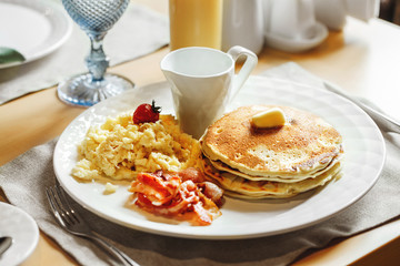 A plate of american breakfast and a cup of juice on a table