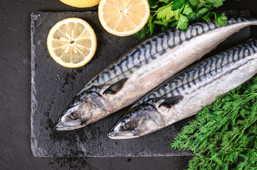 Fresh fish mackerel with lemon and vegetables on dark background