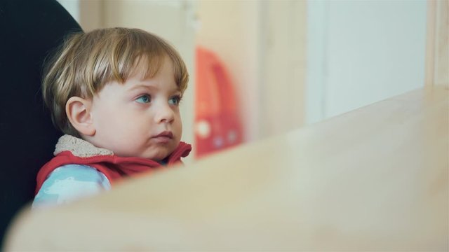 Little kid with blue eyes while watching TV. Young boy watch television in living room. Child watching TV, close up face of little boy.