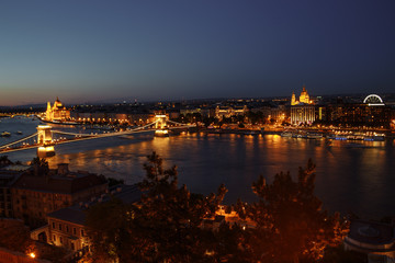 Fototapeta na wymiar night view of the city of Budapest on the Danube river on which ships with illuminated bridge and parliament sail