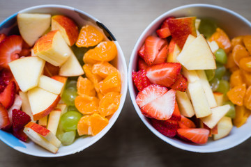 Fruit bowl: Strawberries, apple chunks, grapes and tangerines in a bowl