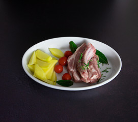 Pork ribs baked with rosemary and potatoes on white plate, top view
