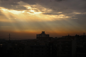 A beautiful landscape of a light beam in the cloudy sky with a background view of a city