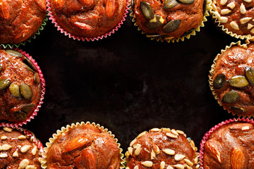 Aromatic muffins with various nuts and seeds as a frame on a black background with copy space. Close up view 