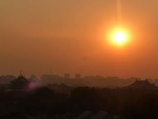 Skyline de Beijing al atardecer con sol y cielo anaranjado sobre en la ciudad prohibida.