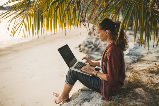 Woman sitting with laptop on the summer beach
