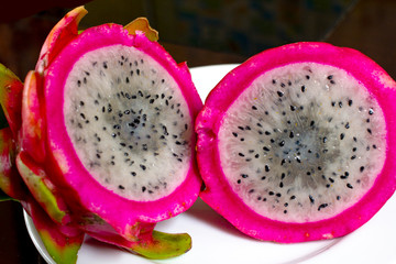 2 slices of tropical, exotic pitaya fruit. Dragon fruit or pitaya fruit Hylocereus undatus. Sectional view on a dark brick  background. 