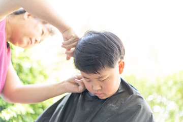 Obraz premium Grandma was cutting hair for her nephew at home in the garden.