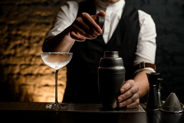 close-up bartender holding in his hand cap from steel shaker.