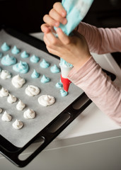 A child makes multi-colored meringues using a pastry bag