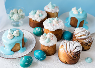 Obraz na płótnie Canvas Beautiful easter cakes with meringues, kraffins on a blue background and blue colored eggs. Beautiful Easter decoration in blue tones