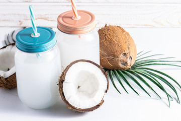 Fresh organic coconut water in mason jars on white wooden background close up. Healthy refreshing veggie drink.