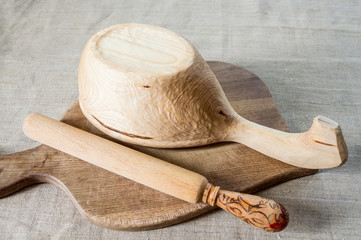 An inverted wooden bowl with a wooden rolling pin on a cutting Board.