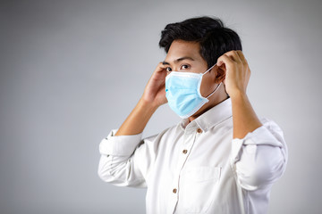 Studio portrait of Asian woman wearing face medical surgical mask, looking at camera, isolated on white background. Mask protection against virus. Covid-19, coronavirus pandemic