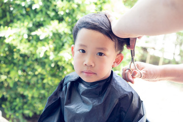 Grandma was cutting hair for her nephew at home in the garden.