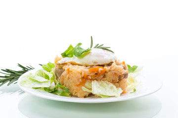 boiled rice with vegetables and fried egg with salad leaves in a plate