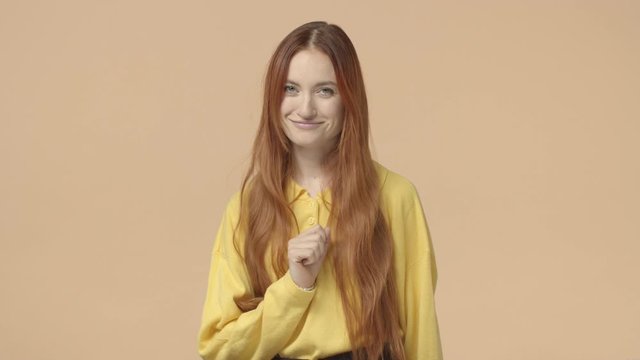 All good, alright. Attractive stylish ginger girl, woman with beautiful long natural red hair smiling and giggle, show okay sign, give permition, approve product, like and agree, yellow background