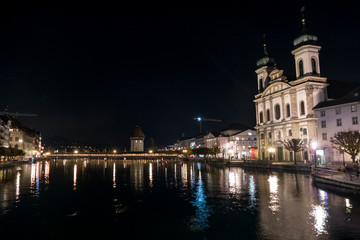 Fototapeta na wymiar Illuminated Lucerne and Chapel Bridge reflect on the river
