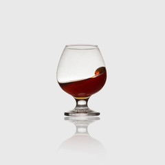 Glass with an alcoholic drink or cognac and splashes on a light background. Isolated, splash.