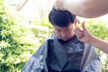 Obraz premium Grandma was cutting hair for her nephew at home in the garden.