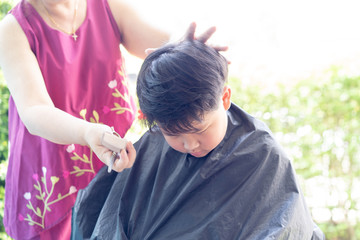 Obraz premium Grandma was cutting hair for her nephew at home in the garden.